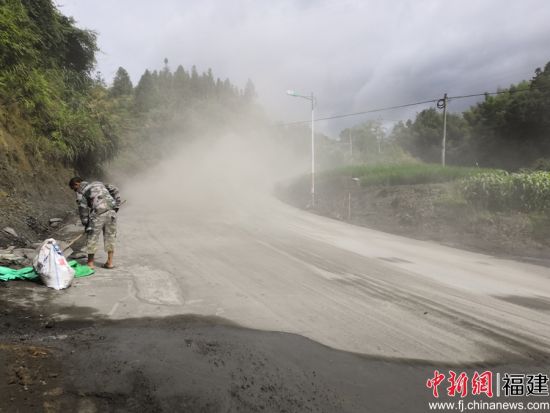 養(yǎng)路工帶上防塵口罩利用鐵鍬、竹掃把等工具清理灑落的水泥料。余思煥 攝